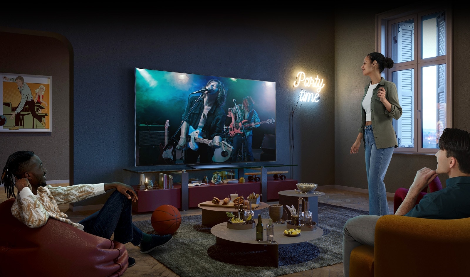 É mostrado o ecrã de um concerto na TV, dois homens estão sentados no sofá e no pufe e uma mulher está de pé a desfrutar do concerto. Na mesa no meio dos amigos, há varios alimentos, tal como pipocas, nachos e refrigerantes.